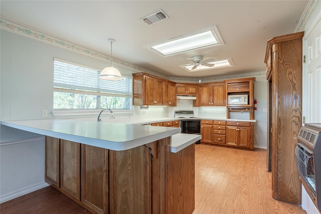 kitchen featuring heating unit, hanging light fixtures, light hardwood / wood-style floors, kitchen peninsula, and white appliances