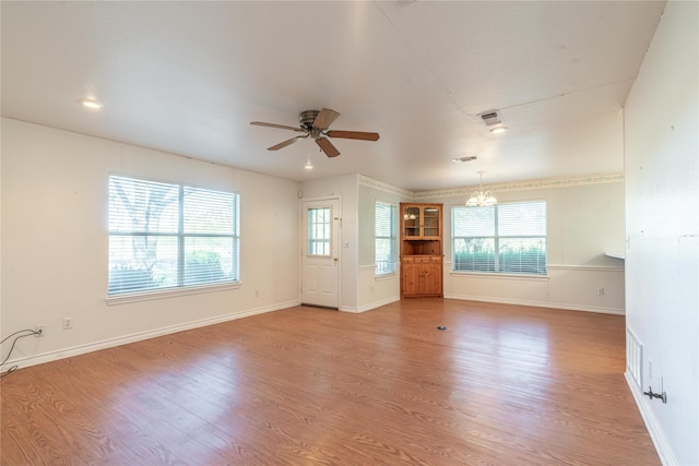 unfurnished living room with ceiling fan with notable chandelier and light wood-type flooring