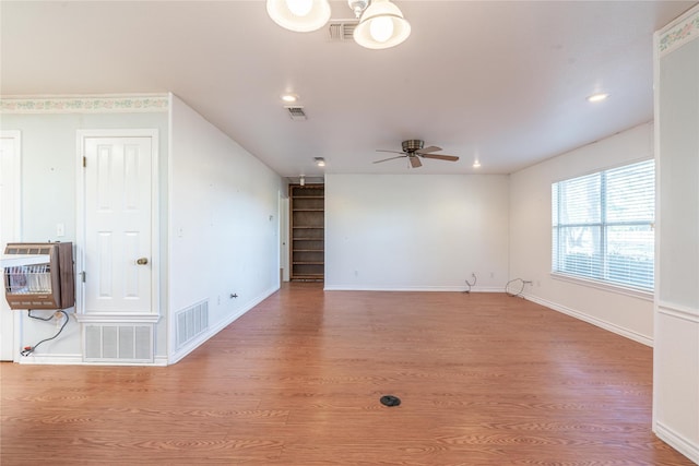 unfurnished living room featuring heating unit, ceiling fan, and light hardwood / wood-style flooring