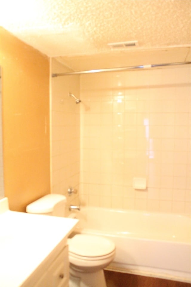 full bathroom featuring tiled shower / bath combo, toilet, and vanity