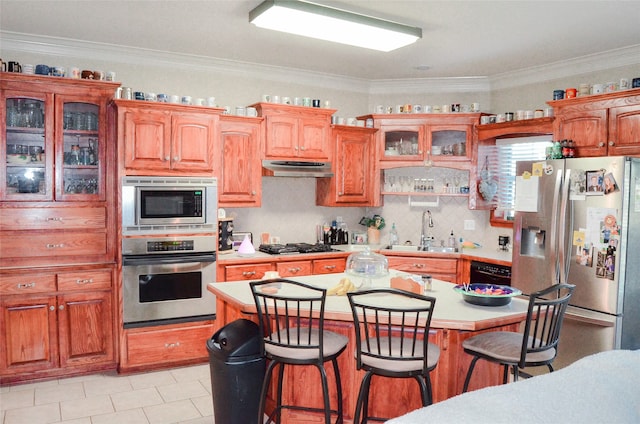 kitchen with appliances with stainless steel finishes, sink, crown molding, and a breakfast bar