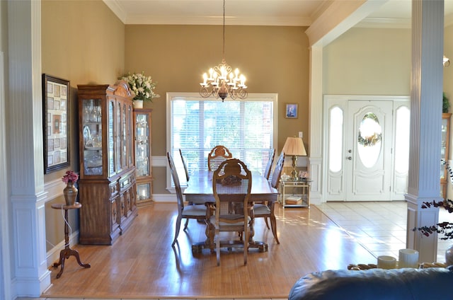 dining room featuring a high ceiling, light wood-type flooring, a chandelier, and crown molding