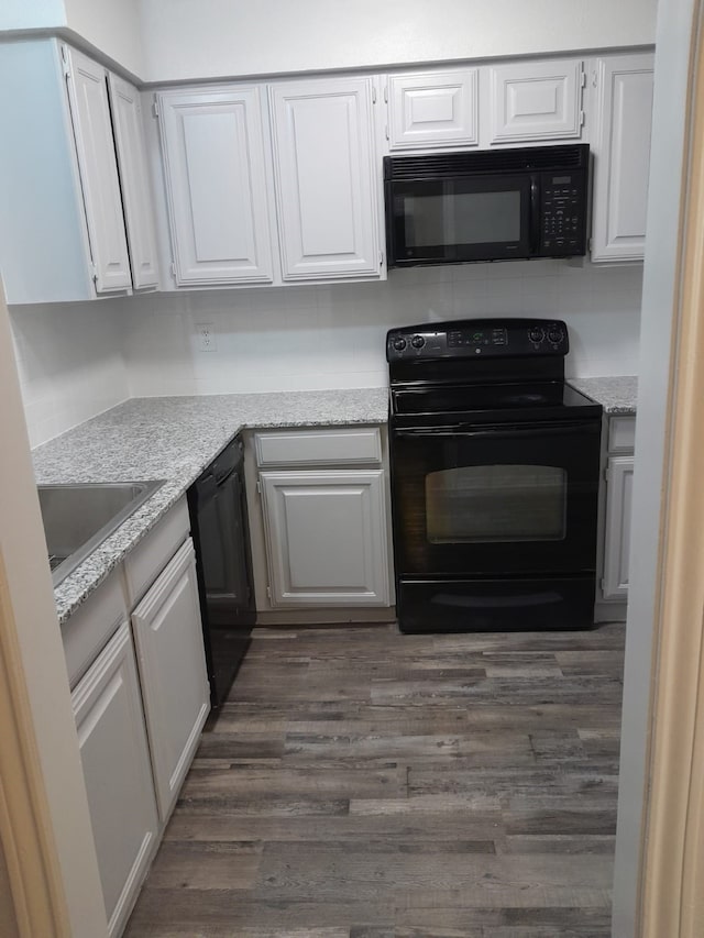 kitchen with dark hardwood / wood-style flooring, black appliances, sink, light stone countertops, and white cabinetry