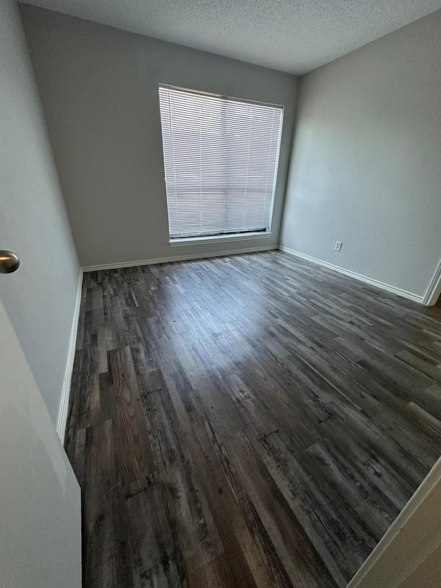 empty room with a textured ceiling and dark hardwood / wood-style floors