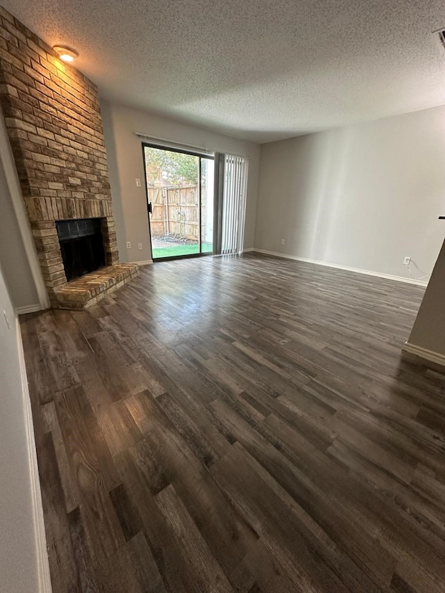 unfurnished living room featuring a fireplace, a textured ceiling, and dark hardwood / wood-style flooring