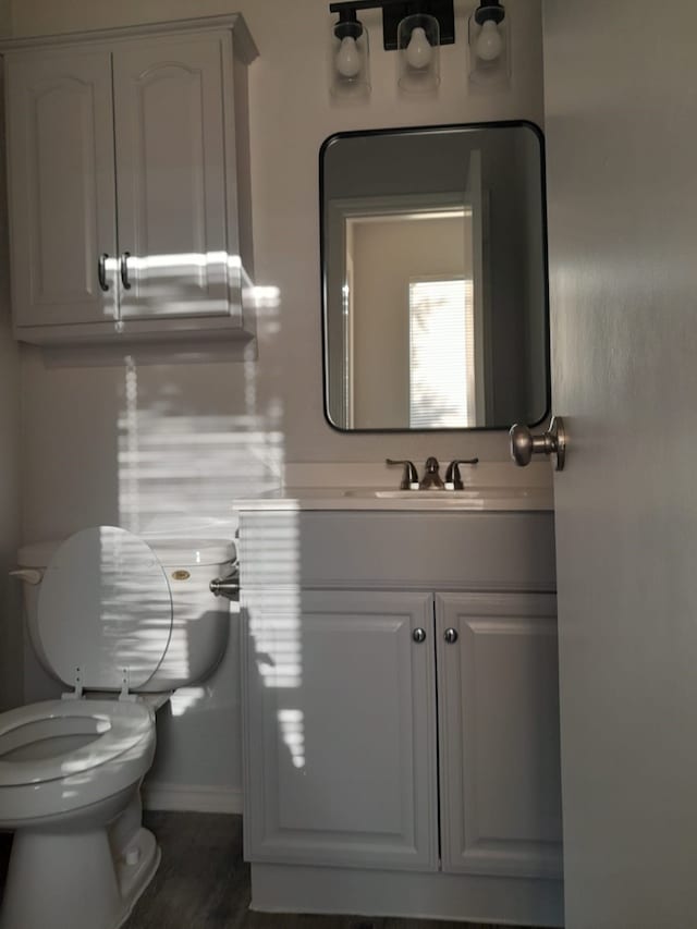 bathroom with toilet, vanity, and hardwood / wood-style floors