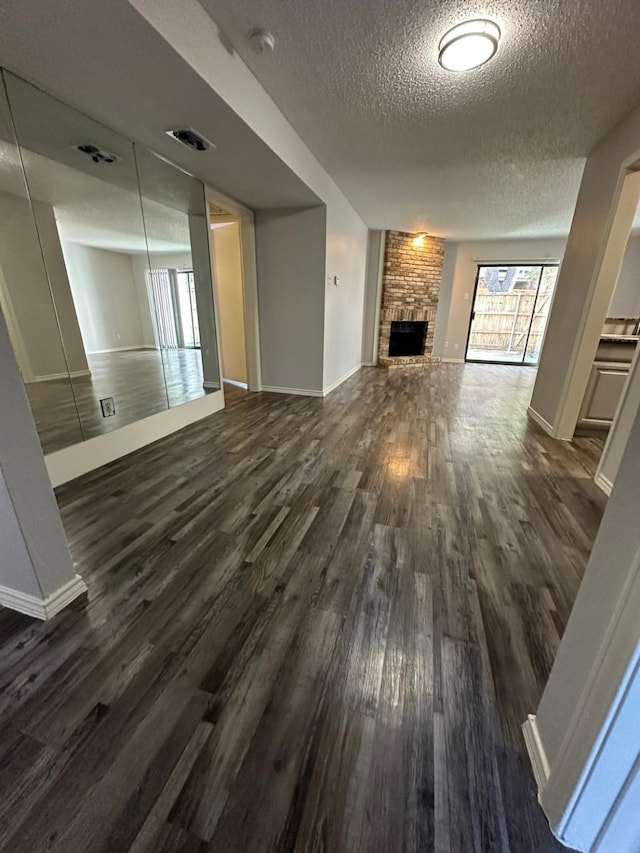 unfurnished living room featuring a textured ceiling, a fireplace, and dark hardwood / wood-style floors