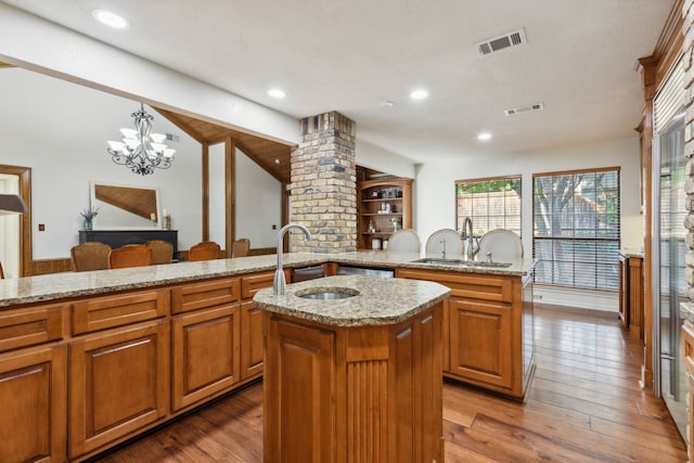 kitchen featuring wood-type flooring, decorative light fixtures, sink, decorative columns, and a center island