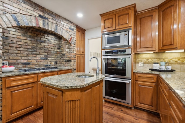 kitchen with light stone countertops, a kitchen island, appliances with stainless steel finishes, and hardwood / wood-style flooring