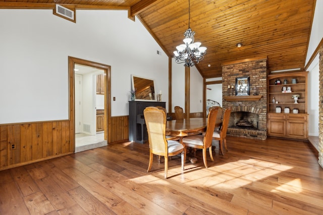 dining area with built in shelves, a chandelier, wood-type flooring, and a fireplace