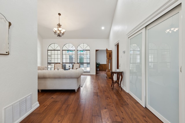 living room featuring dark hardwood / wood-style flooring, a chandelier, and vaulted ceiling