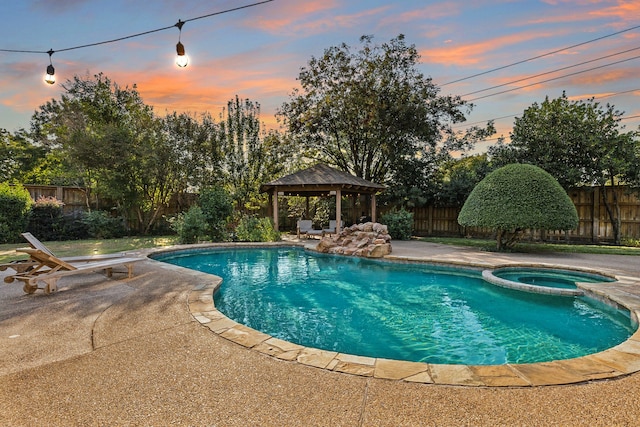 pool at dusk featuring a patio, a gazebo, and an in ground hot tub