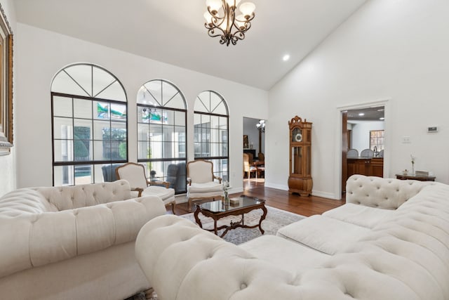 living room featuring hardwood / wood-style flooring, high vaulted ceiling, and a notable chandelier