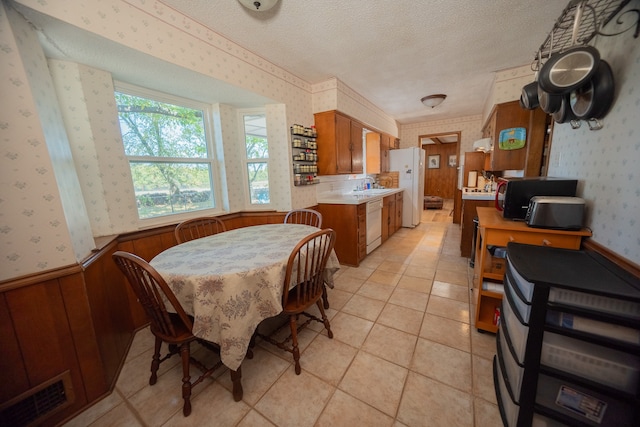 tiled dining area featuring wood walls and a textured ceiling