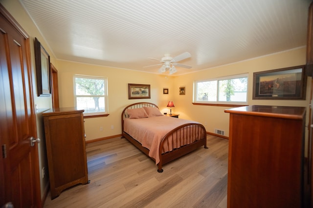 bedroom with ceiling fan, multiple windows, and light wood-type flooring