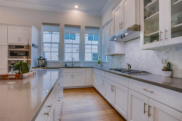 kitchen featuring light wood-type flooring, white cabinetry, ornamental molding, and decorative backsplash