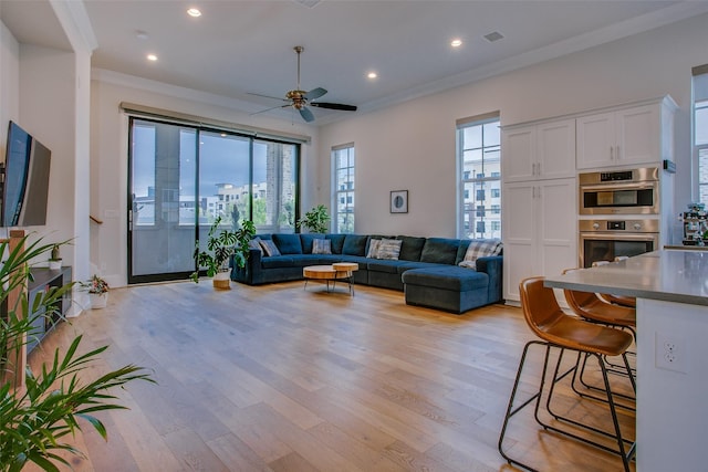 living room featuring crown molding, light wood-type flooring, and ceiling fan