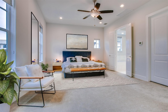 bedroom with light colored carpet, ensuite bath, and ceiling fan