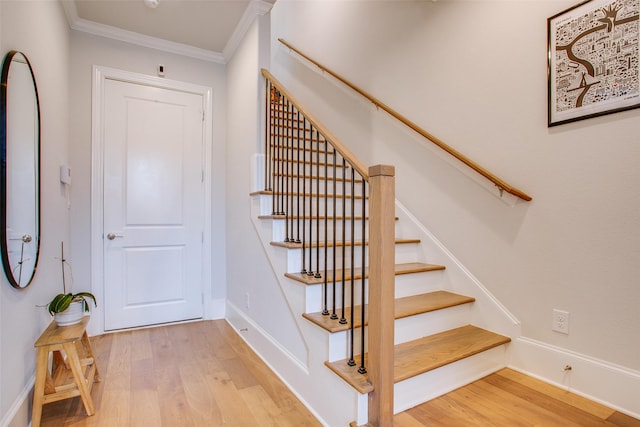 stairs featuring hardwood / wood-style flooring and ornamental molding