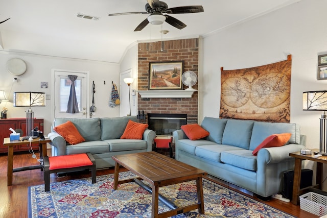 living room featuring wood-type flooring, crown molding, a brick fireplace, lofted ceiling, and ceiling fan