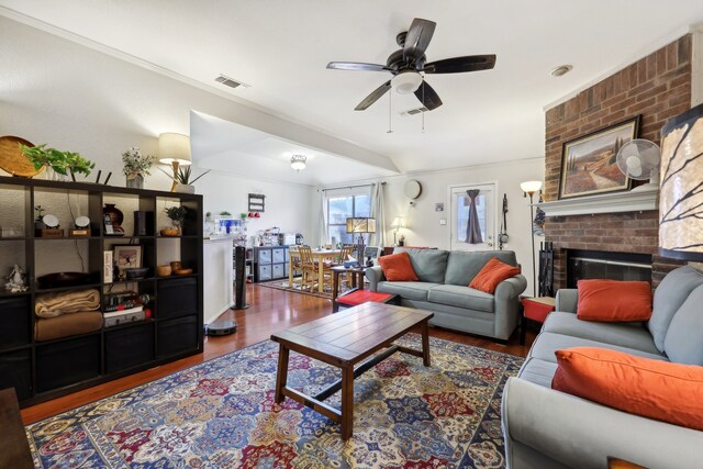 living room featuring ornamental molding, wood-type flooring, ceiling fan, and a fireplace