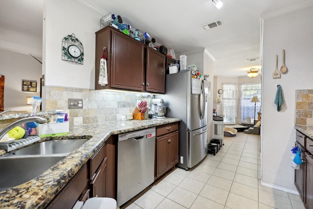 kitchen with ornamental molding, appliances with stainless steel finishes, sink, and light stone countertops