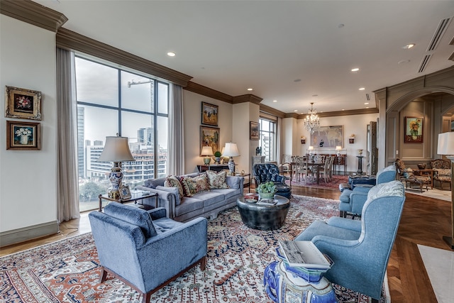 living room featuring hardwood / wood-style flooring, crown molding, and an inviting chandelier