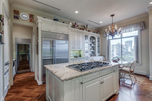 kitchen with appliances with stainless steel finishes, hanging light fixtures, white cabinets, beverage cooler, and dark parquet flooring