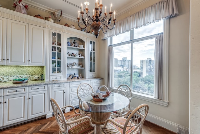 dining area with ornamental molding, dark parquet flooring, and an inviting chandelier