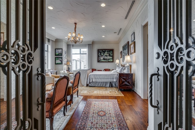 bedroom with ornamental molding, wood-type flooring, a textured ceiling, and a notable chandelier