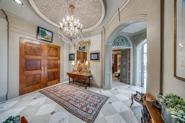 entrance foyer with a chandelier and crown molding