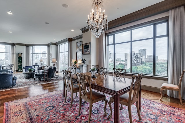 dining room with parquet flooring, a notable chandelier, a healthy amount of sunlight, and crown molding