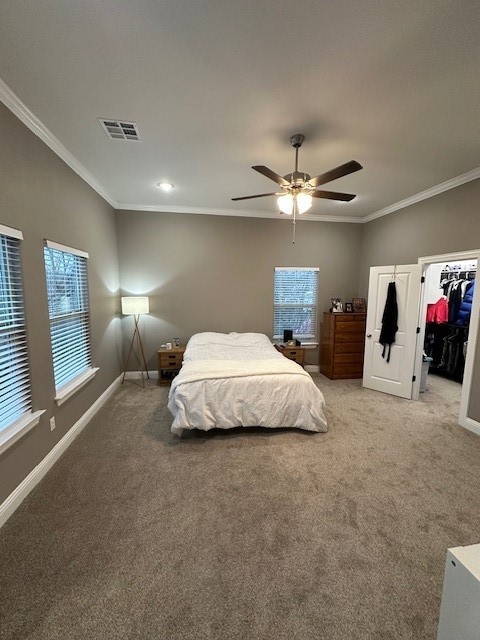 carpeted bedroom featuring ornamental molding, multiple windows, ceiling fan, and a closet