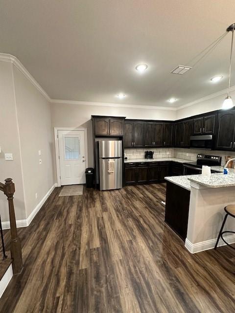 kitchen featuring decorative backsplash, appliances with stainless steel finishes, light stone countertops, hanging light fixtures, and dark hardwood / wood-style flooring