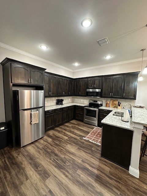 kitchen featuring dark hardwood / wood-style flooring, kitchen peninsula, hanging light fixtures, dark brown cabinets, and appliances with stainless steel finishes