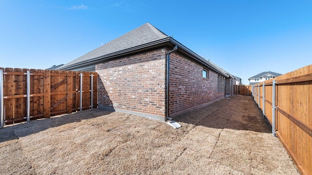 view of property exterior with a fenced backyard, roof with shingles, and brick siding