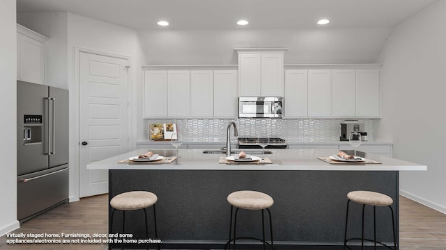 kitchen with stainless steel appliances, a breakfast bar, wood finished floors, and white cabinetry