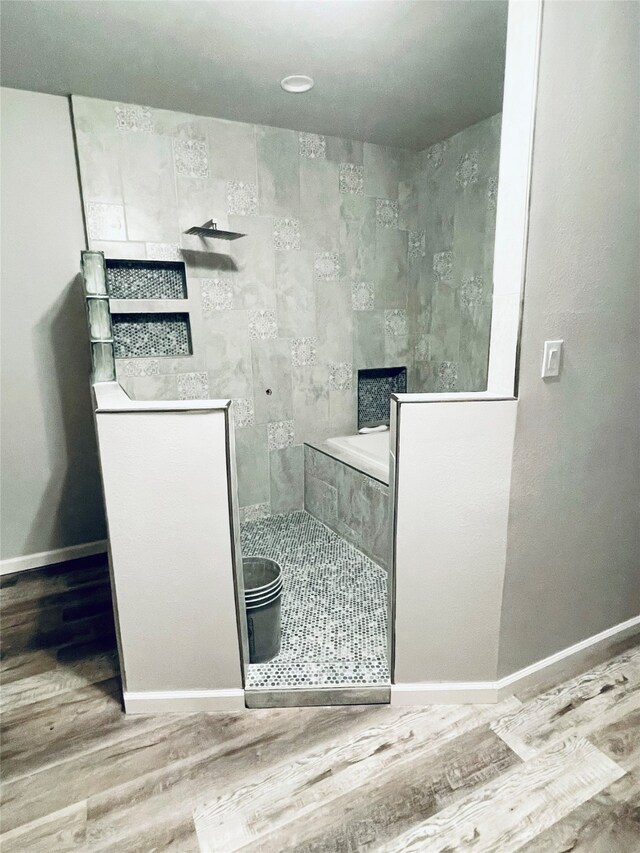 bathroom featuring wood finished floors, baseboards, and a walk in shower