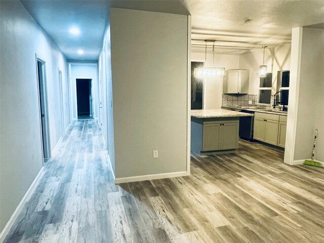 kitchen featuring backsplash, baseboards, decorative light fixtures, light countertops, and wood finished floors