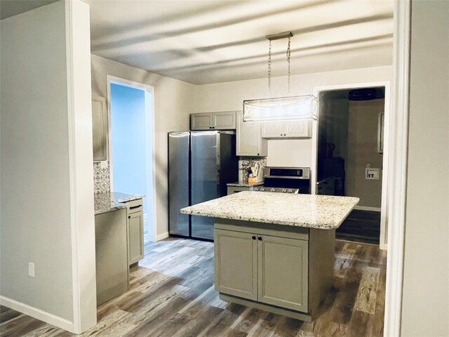 kitchen featuring dark wood-style floors, a center island, stainless steel appliances, and baseboards