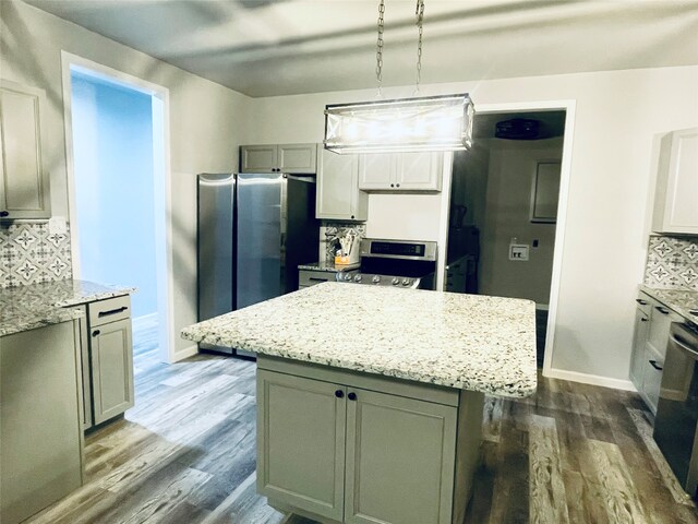 kitchen featuring dark wood-type flooring, backsplash, light stone countertops, and appliances with stainless steel finishes