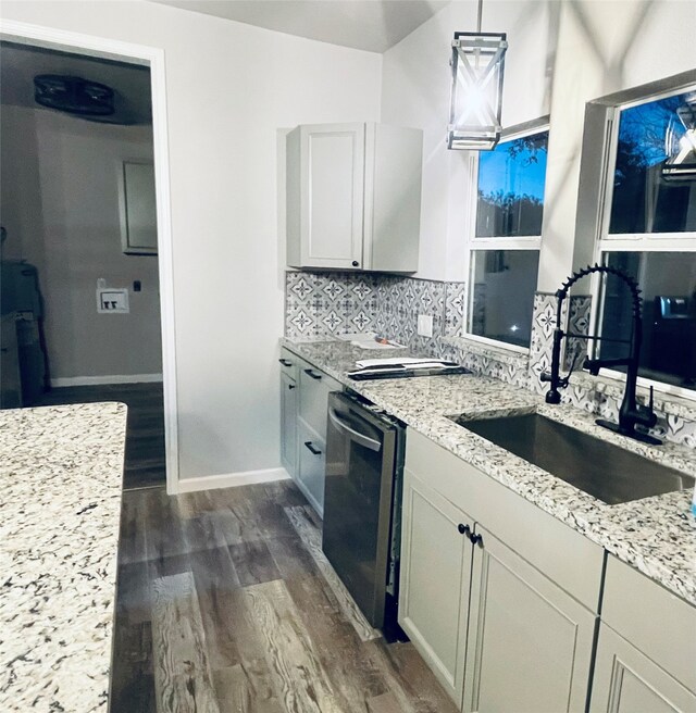 kitchen featuring a sink, backsplash, dark wood-style floors, light stone countertops, and dishwasher