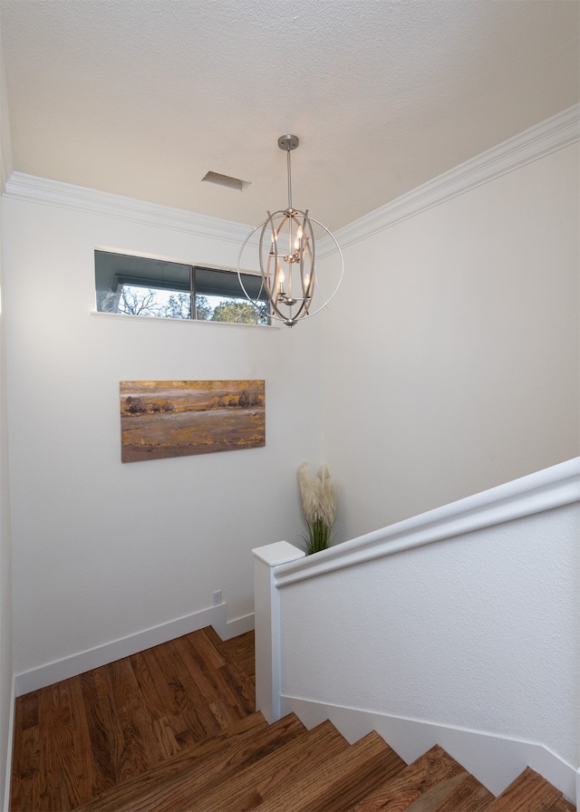 stairway with a chandelier, hardwood / wood-style flooring, and crown molding