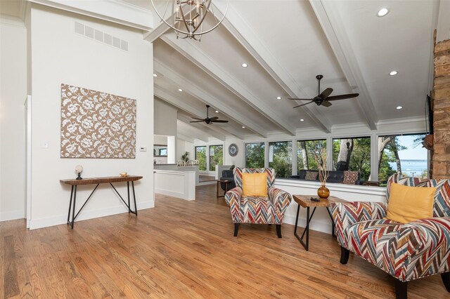 sitting room with lofted ceiling with beams, ceiling fan with notable chandelier, and light hardwood / wood-style flooring