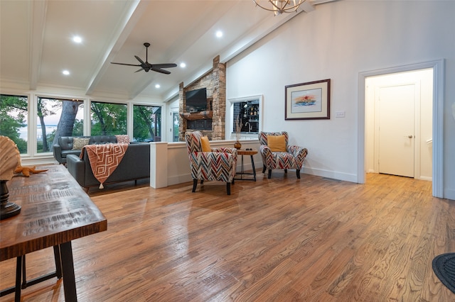 living room with beamed ceiling, ceiling fan with notable chandelier, light wood-type flooring, and high vaulted ceiling