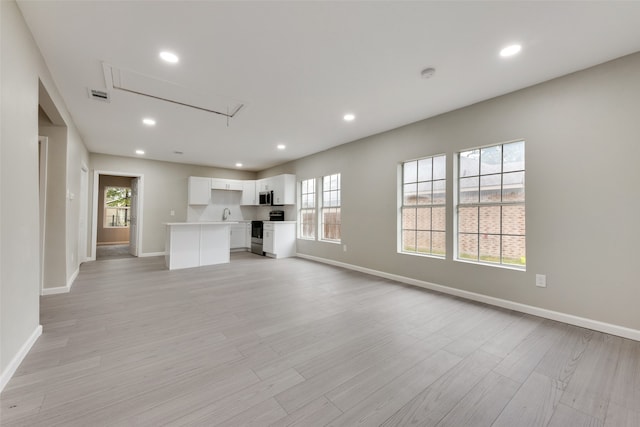 unfurnished living room featuring light hardwood / wood-style floors and sink