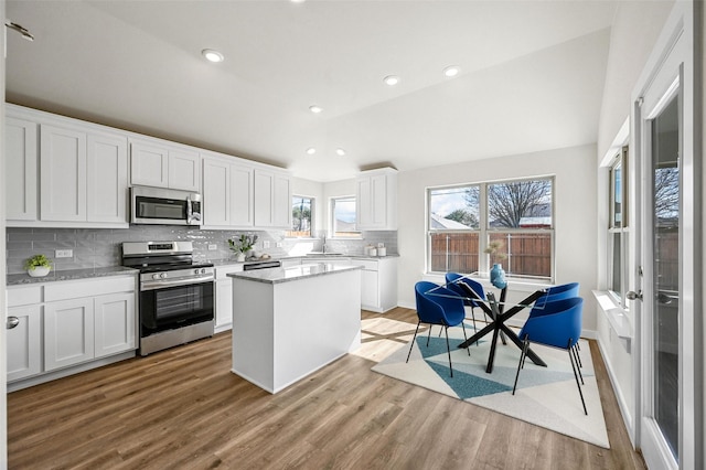 kitchen with appliances with stainless steel finishes, white cabinetry, tasteful backsplash, and a center island