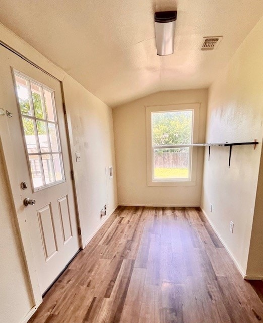 interior space featuring a textured ceiling, light hardwood / wood-style flooring, and lofted ceiling