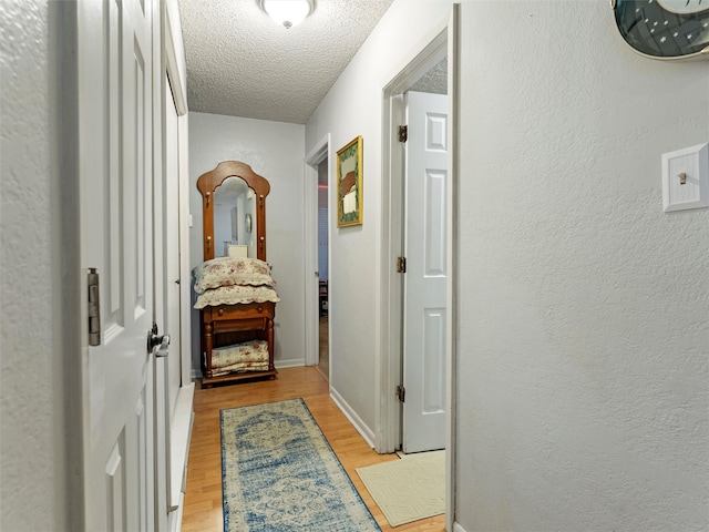 corridor featuring a textured ceiling and light hardwood / wood-style flooring