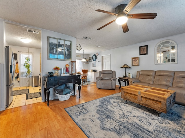 living room with ceiling fan, wood-type flooring, and a textured ceiling